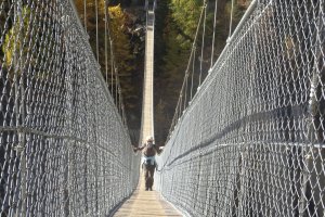 Wandelaar op de hangbrug in de Goms-vallei bij Muehlebach in herfstkleuren, Aletsch Arena, Wallis